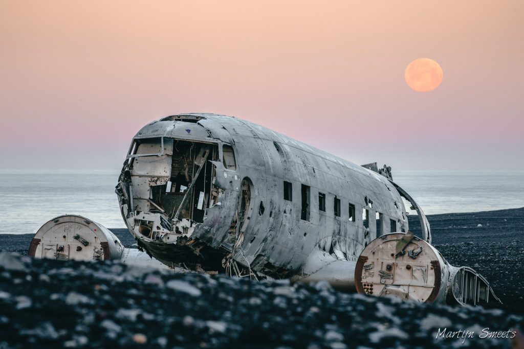 Volle maan achter het DC-3 vliegtuigwrak op Sólheimasandur, IJsland
